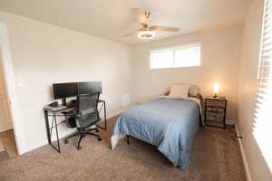 Carpeted bedroom featuring a ceiling fan and a desk