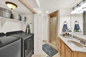 Laundry area featuring light tile patterned flooring, washing machine and clothes dryer, and recessed lighting