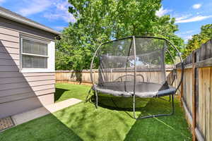 Fenced backyard featuring a trampoline