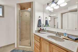 Bathroom with vanity, a shower stall, light tile patterned flooring, and a closet
