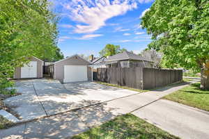 View of side of property featuring driveway, a garage, and a shed