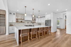 Kitchen featuring open shelves, glass insert cabinets, light stone counters, and white cabinetry