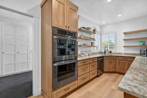 Kitchen featuring stainless steel appliances, light stone counters, open shelves, a textured ceiling, and recessed lighting