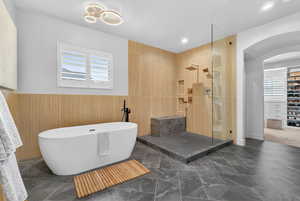 Full bathroom featuring a freestanding bath, walk in shower, a wainscoted wall, and recessed lighting