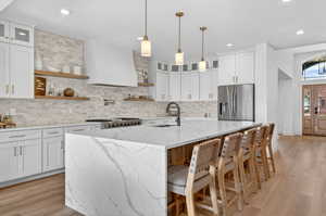 Kitchen featuring light stone countertops, glass fronted cabinets, and white cabinetry