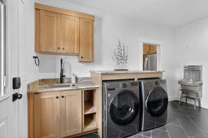 Laundry room with washing machine and dryer, dark tile patterned flooring, and cabinet space