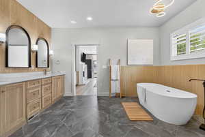 Bathroom with double vanity, a freestanding tub, and recessed lighting