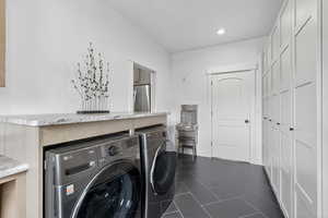 Laundry room featuring separate washer and dryer, dark tile patterned floors, and recessed lighting