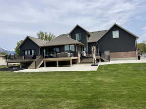 Back of property featuring a deck, a lawn, and brick siding