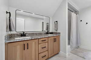 Full bath with double vanity and shower / tub combo with curtain