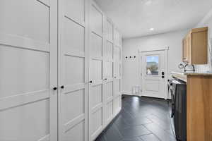 Laundry area with recessed lighting, a textured ceiling, cabinet space, dark tile patterned floors, and washing machine and dryer