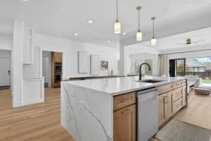 Kitchen with a ceiling fan, an island with sink, stainless steel appliances, open floor plan, and light stone countertops