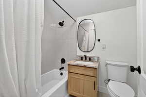 Full bathroom featuring shower / bath combo, vanity, and a textured ceiling
