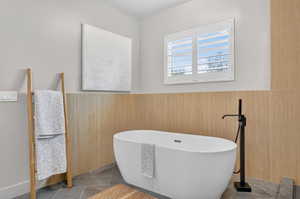 Full bath featuring wainscoting, a freestanding bath, and tile patterned floors