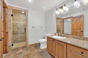 Bathroom with vanity, a shower stall, and dark stone finish flooring