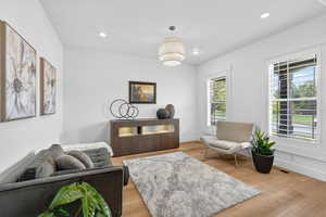Living area with light wood-type flooring and recessed lighting