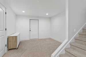 Finished below grade area featuring light colored carpet and recessed lighting