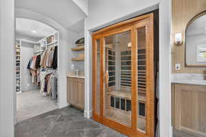 Walk in closet featuring arched walkways and dark carpet