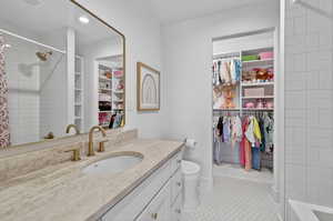 Full bathroom featuring a shower with curtain, vanity, a spacious closet, and light tile patterned floors