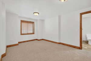 Unfurnished room featuring light carpet and baseboards