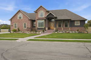 View of front of house with a front yard, brick siding, and a shingled roof