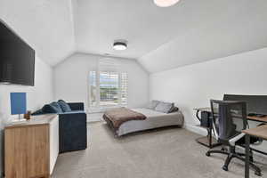 Bedroom featuring a desk, a textured ceiling, and light colored carpet