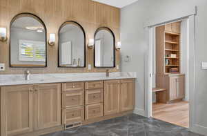 Full bath featuring double vanity and dark marble finish floors
