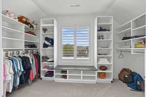 Walk in closet featuring light carpet and vaulted ceiling