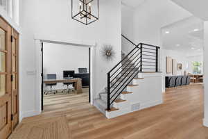 Staircase featuring wood finished floors, suspended lighting, and a high ceiling