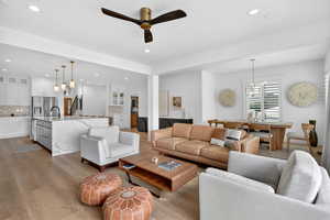 Living area with suspended lighting, ceiling fan, and light wood finished floors