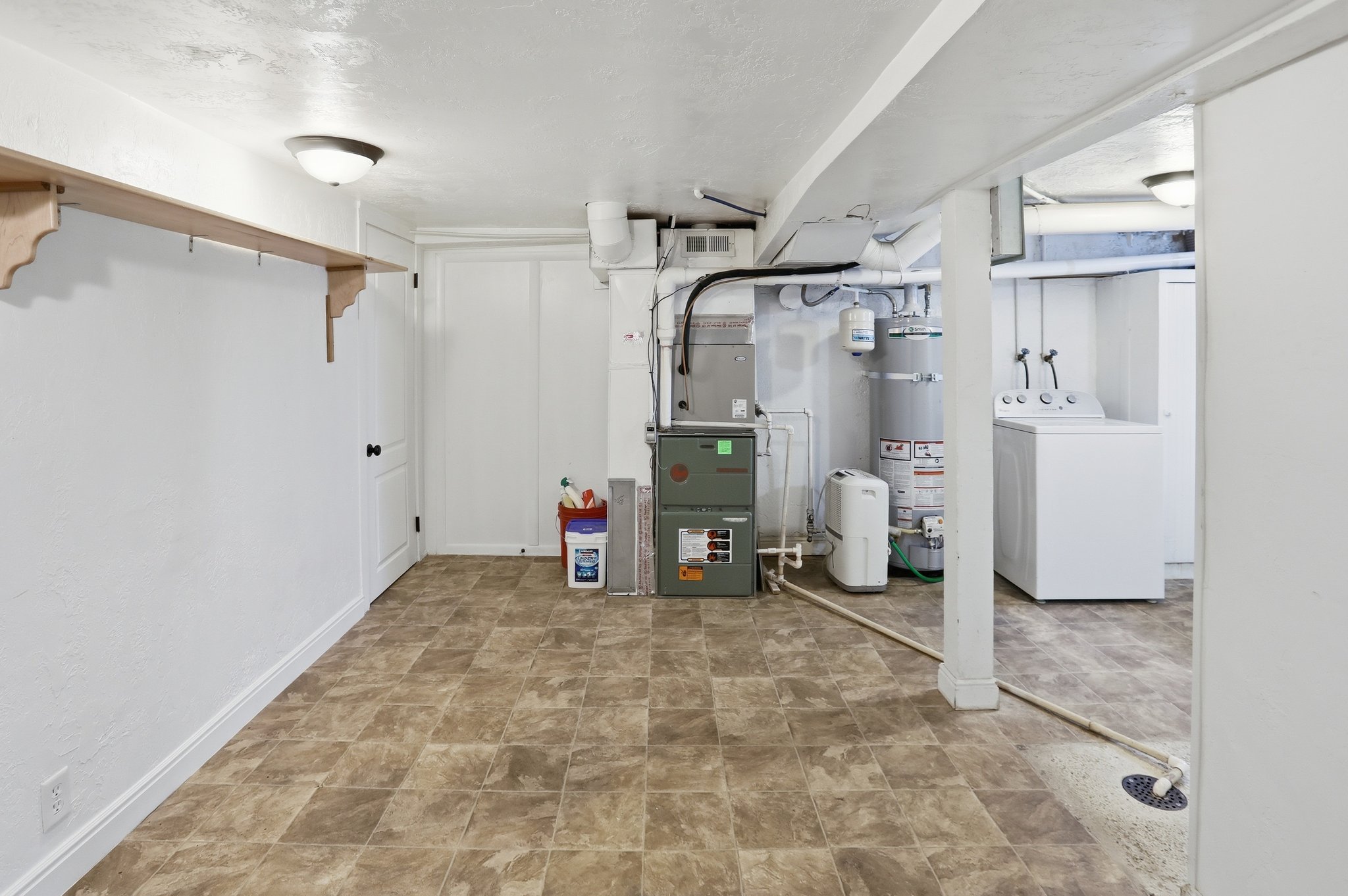 Finished below grade area with washer / clothes dryer, stone finish floors, and water heater
