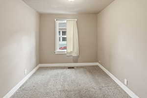 Unfurnished room featuring light carpet and baseboards