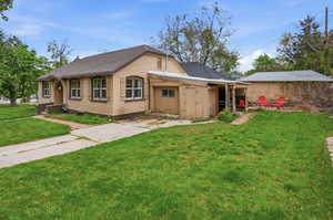View of front facade featuring a front lawn, a shingled roof, and stucco siding