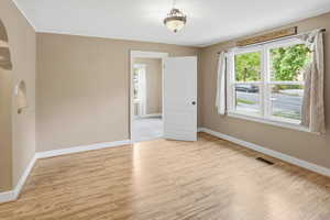 Empty room featuring light wood-type flooring, a textured ceiling, arched walkways, and healthy amount of natural light