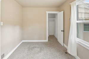 Unfurnished bedroom with light carpet and a closet