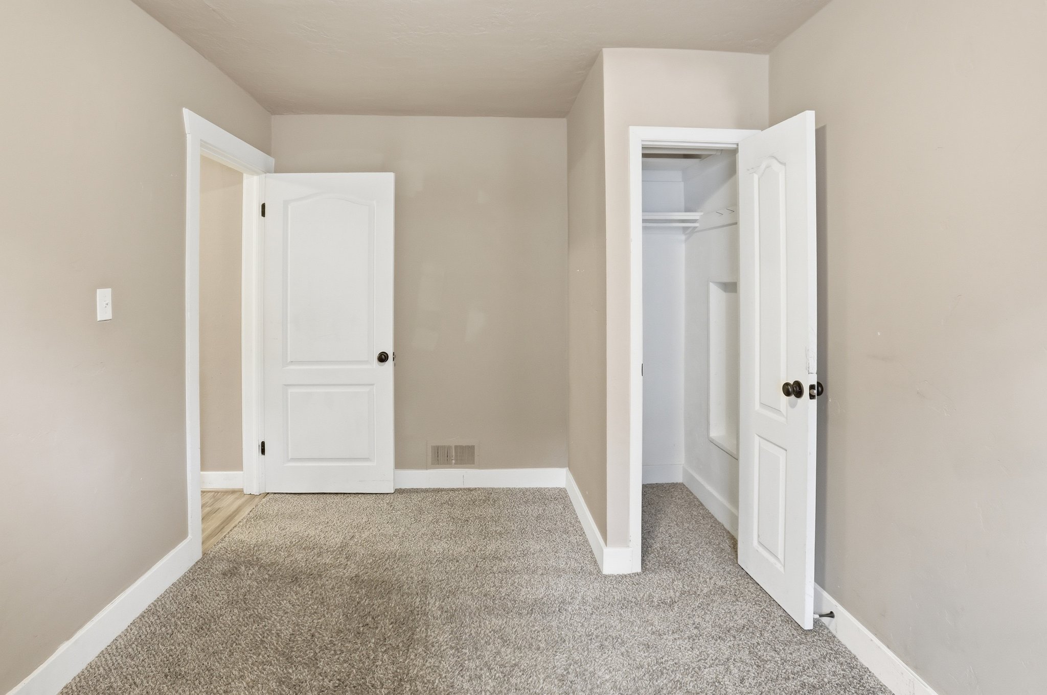 Unfurnished bedroom with light colored carpet and baseboards