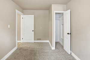 Unfurnished bedroom with light colored carpet and baseboards