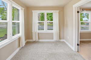 Empty room with light colored carpet and plenty of natural light