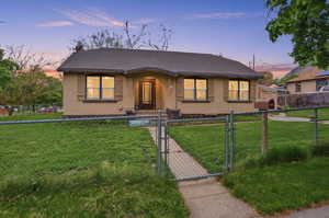 Bungalow-style house featuring a gate, roof with shingles, a fenced front yard, and stucco siding