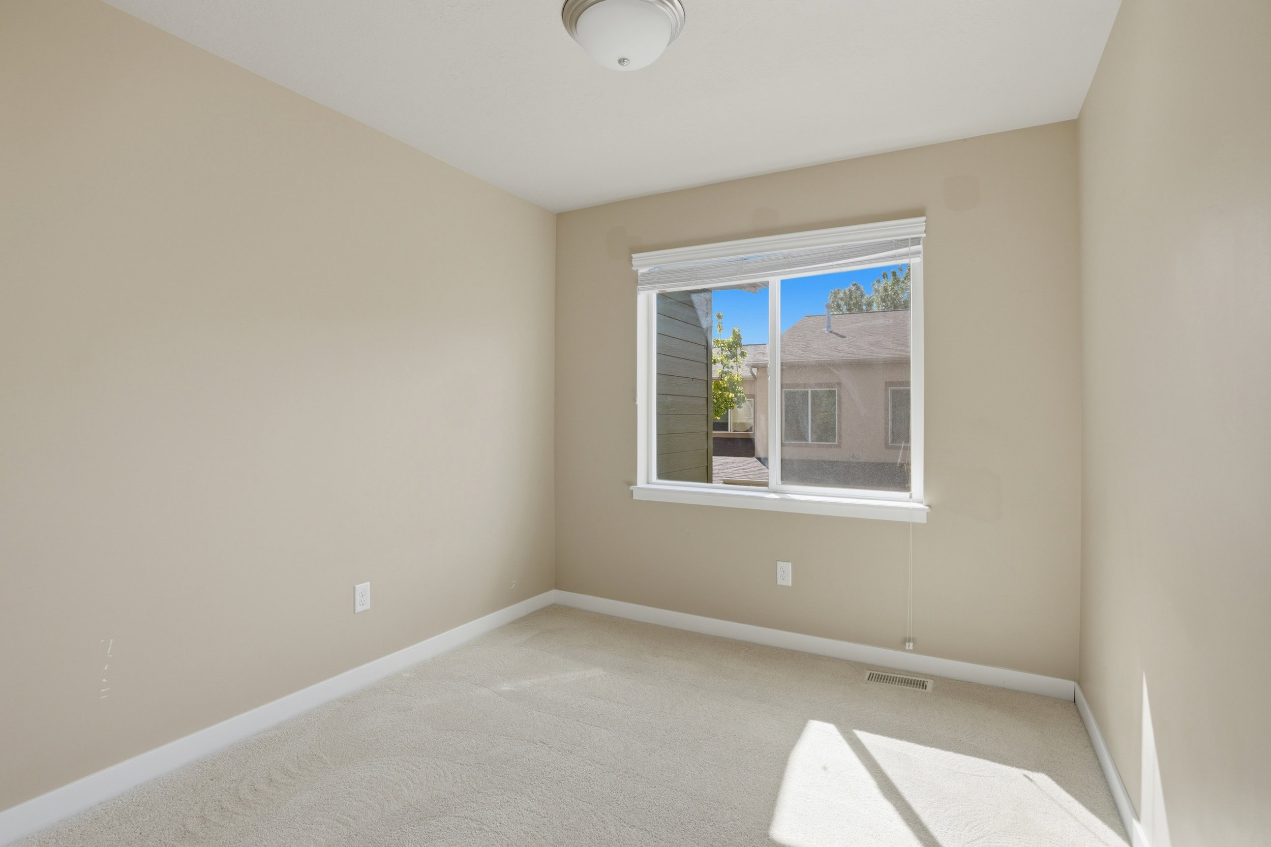 Unfurnished room featuring light carpet and baseboards