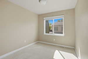 Unfurnished room featuring light carpet and baseboards