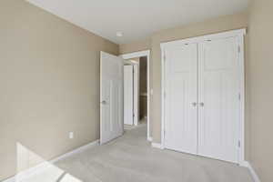 Unfurnished bedroom featuring light carpet and a closet