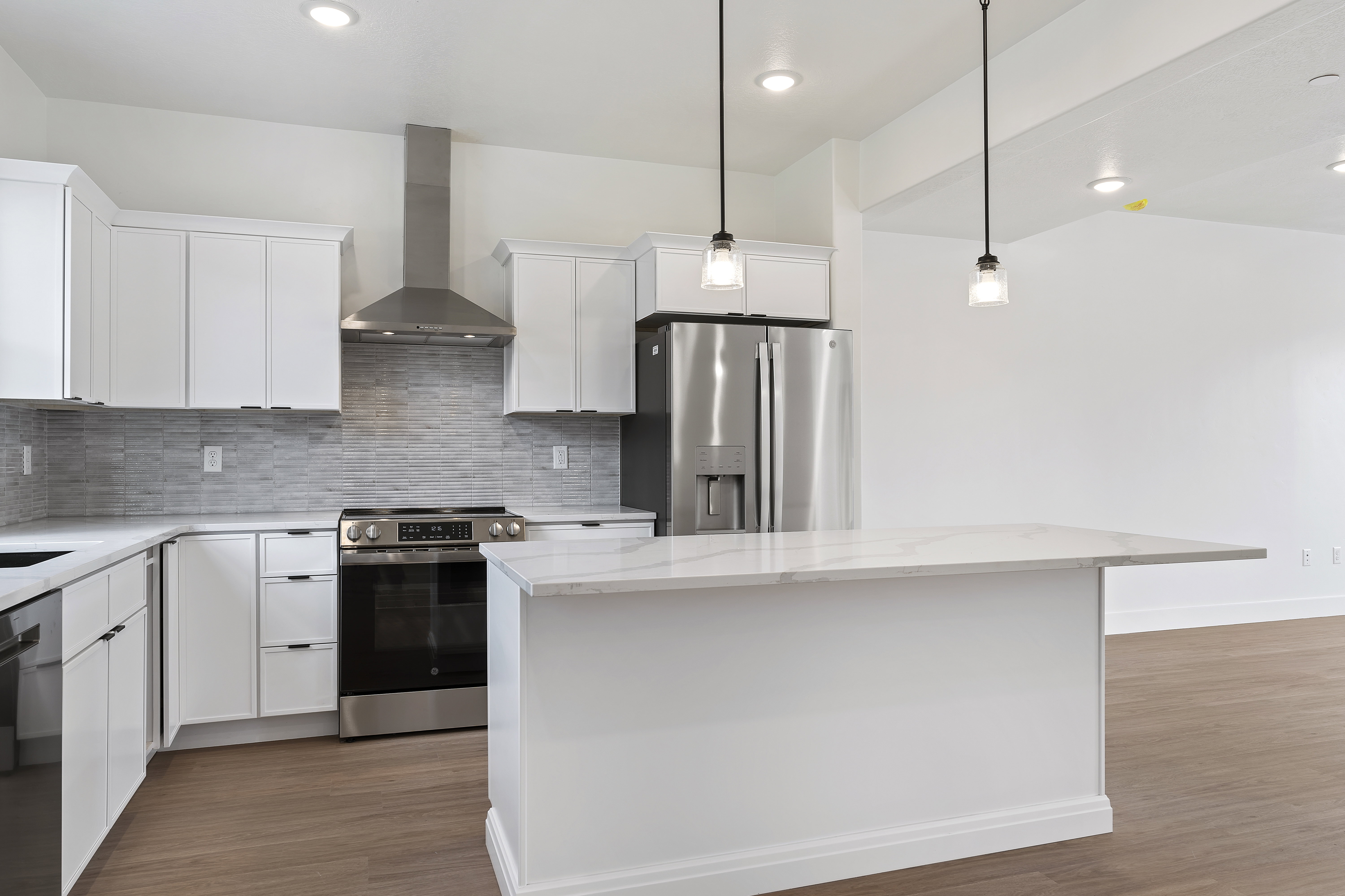 Kitchen with stainless steel appliances, white cabinetry, a center island, dark wood-style flooring, and light stone counters