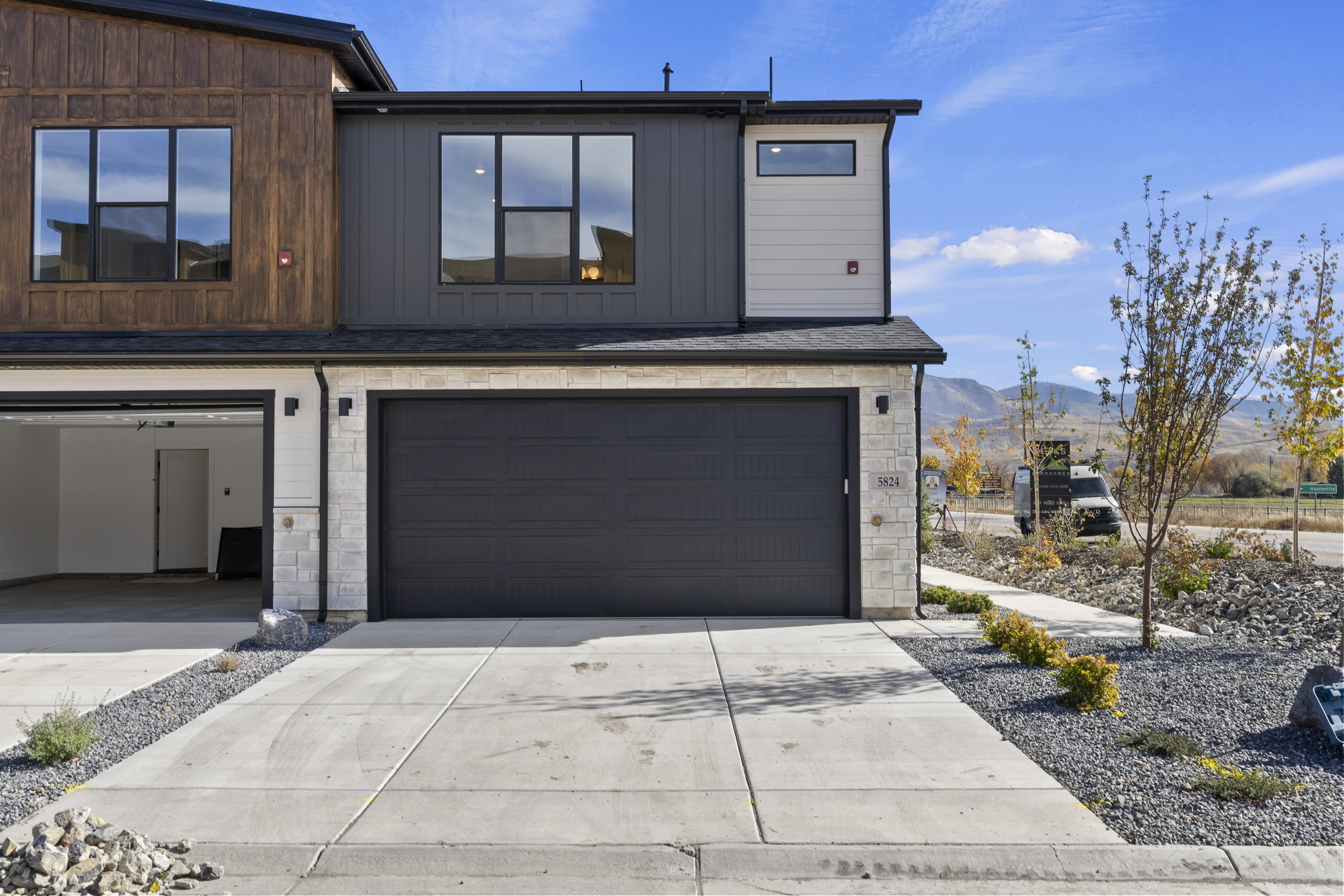 View of front facade featuring stone siding, driveway, an attached garage, and a mountain view