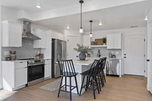 Kitchen featuring stainless steel appliances, white cabinetry, open shelves, and light wood-style floors