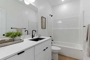 Bathroom with vanity, washtub / shower combination, and light wood-style flooring