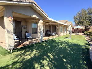 Rear view of house featuring a putting green, a patio, stucco siding, and a tile roof