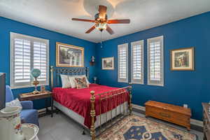 Bedroom featuring a ceiling fan, light tile patterned floors, and a textured ceiling