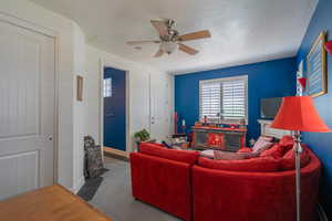 Living room featuring a ceiling fan, tile patterned floors, and a textured ceiling