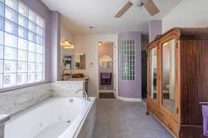 Bathroom with vanity, ceiling fan, a tub with jets, dark tile patterned flooring, and a relaxing sauna